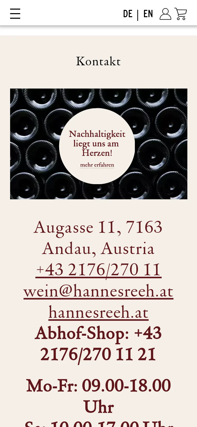 The mobile version presents a similar layout with the wine bottle hero image and central sustainability message at the top. The contact details, including the address, phone number, and email, are stacked vertically in large text below the image. The navigation menu is condensed into a hamburger icon at the top left, and language options are visible at the top right.