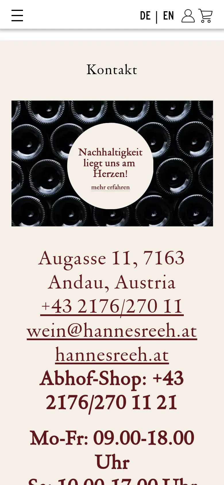 The mobile version presents a similar layout with the wine bottle hero image and central sustainability message at the top. The contact details, including the address, phone number, and email, are stacked vertically in large text below the image. The navigation menu is condensed into a hamburger icon at the top left, and language options are visible at the top right.