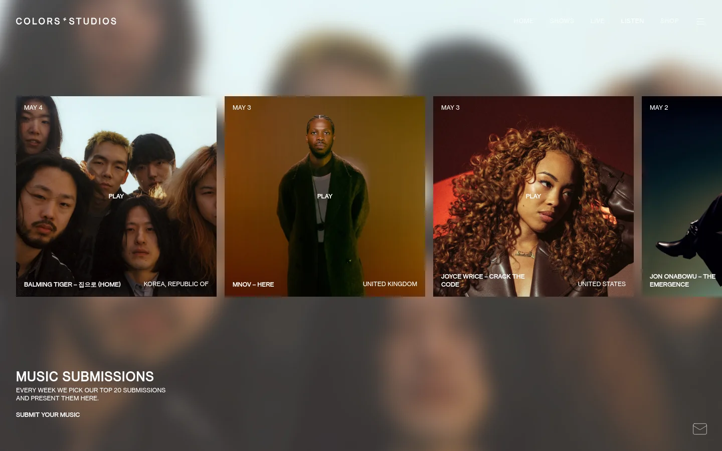 The desktop page features a dark, minimalist layout with a grid of large music submission cards. Each card displays a high-quality artist photograph, the release date, artist name, song title, country of origin, and a 'PLAY' call to action. A header contains the COLORS*STUDIOS logo and navigation links, while a footer section invites users to submit their own music.