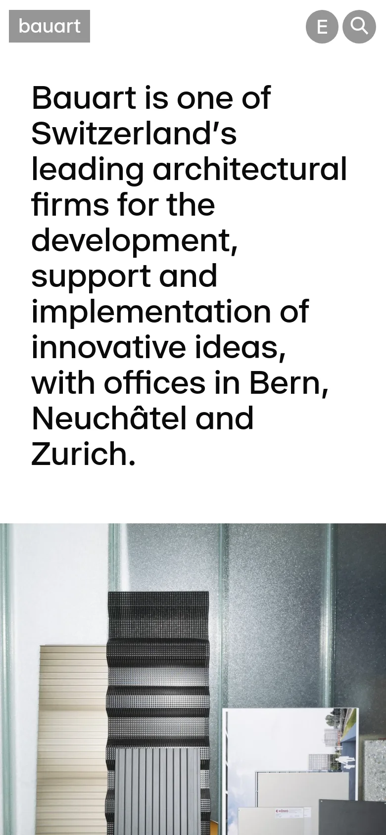 The mobile version presents a vertically stacked layout with the large mission statement headline appearing first in bold black text. A single architectural detail photograph follows the text, filling the width of the screen. The navigation is condensed, and the overall aesthetic remains minimalist with high contrast between the black text and white background.