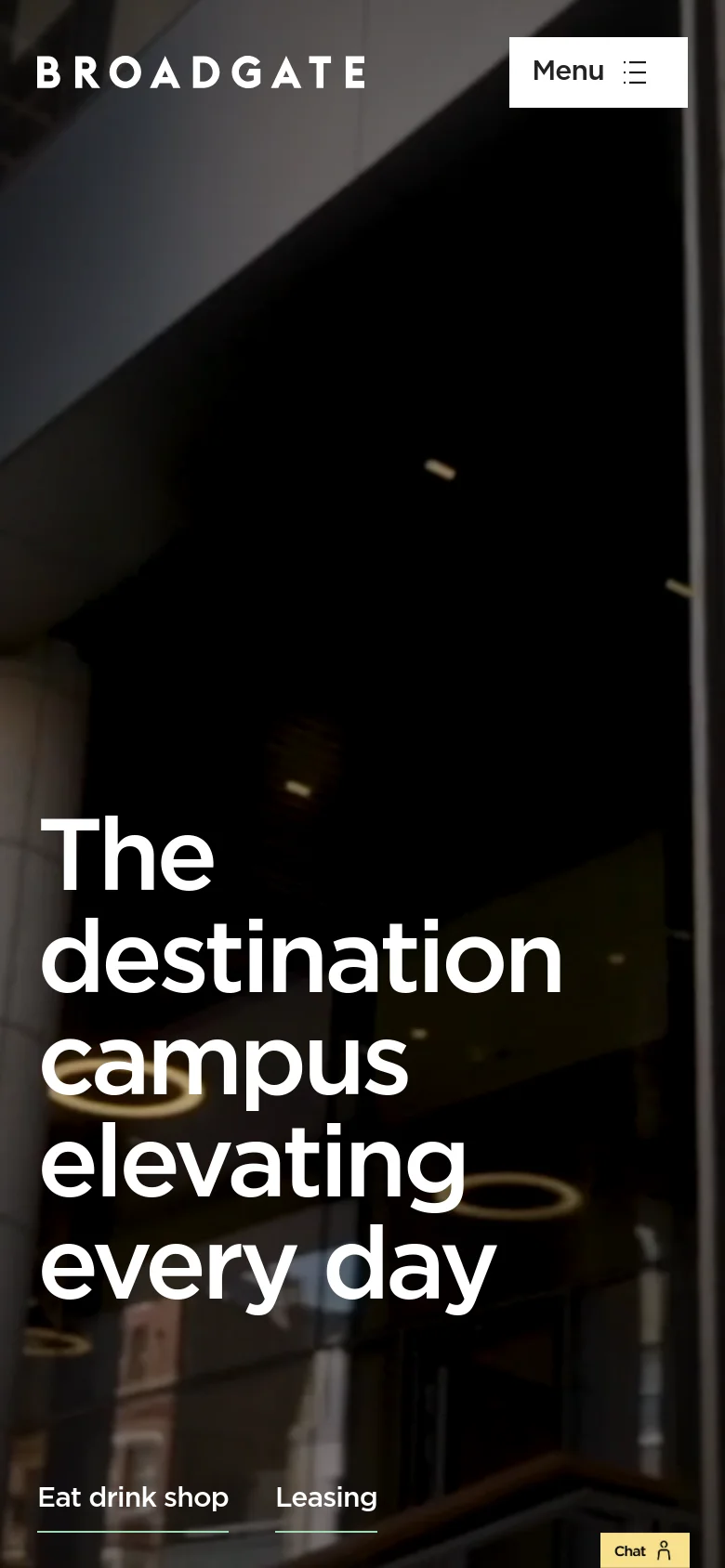 The mobile version simplifies the layout, replacing the top navigation bar with a prominent 'Menu' button in the upper right corner. The hero headline 'The destination campus elevating every day' is stacked vertically to fit the narrow screen, and the bottom navigation links for 'Eat drink shop' and 'Leasing' are centered above a chat icon.