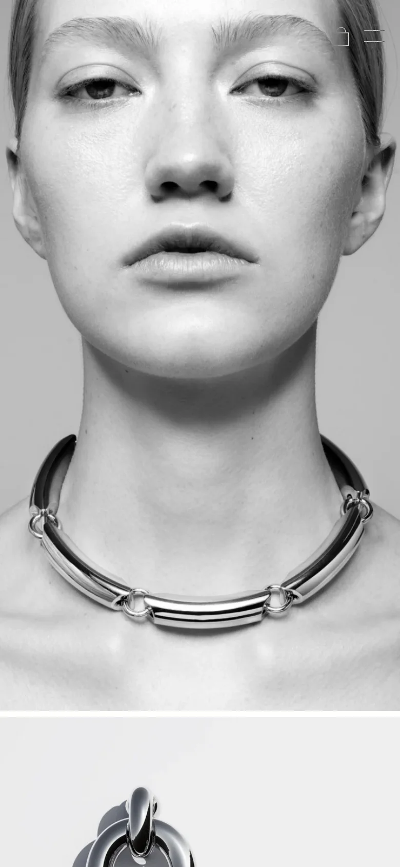 The mobile version maintains the minimalist aesthetic but transitions to a single-column vertical scroll. The large hero imagery of models wearing jewelry remains prominent at the top, followed by a stacked list of product cards showing jewelry items and prices. Navigation is condensed into a hamburger menu icon in the top right corner.