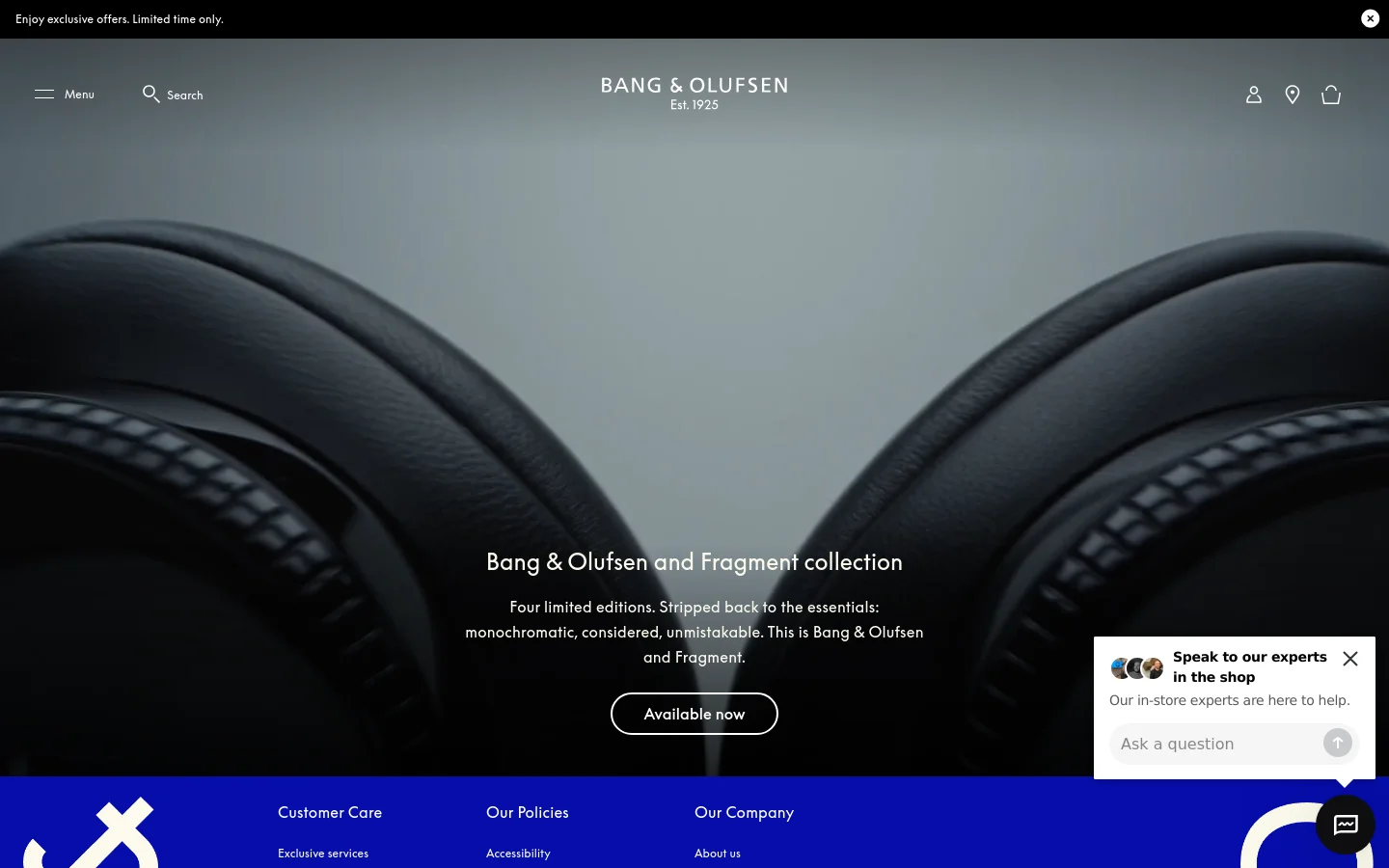 Desktop homepage featuring a large hero image of black headphones against a grey background. The headline 'Bang & Olufsen and Fragment collection' is centered above a description and an 'Available now' call-to-action button. A dark navigation bar at the top includes a menu, search icon, brand logo, user profile, store locator, and shopping bag.
