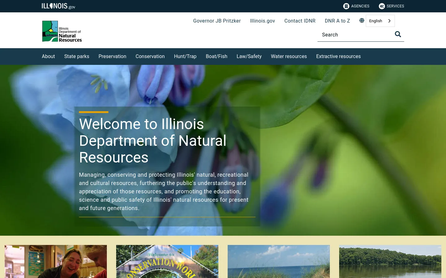 The Illinois Department of Natural Resources homepage features a large hero image of a blue flower with a dark overlay containing the welcome headline and mission statement. A white header includes the agency logo, navigation links for Governor JB Pritzker and Illinois.gov, a search bar, and a dark blue primary navigation menu with categories like State Parks and Conservation. The layout is wide and organized with a clean, professional aesthetic.