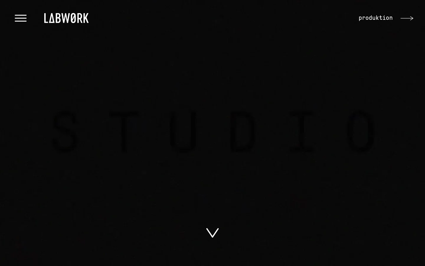 The desktop homepage features a minimalist dark theme with the LABWORK logo and a hamburger menu on the left and a 'produktion' link on the right. A large, subtle 'STUDIO' text is centered against a textured black background, with a downward arrow indicating more content below.
