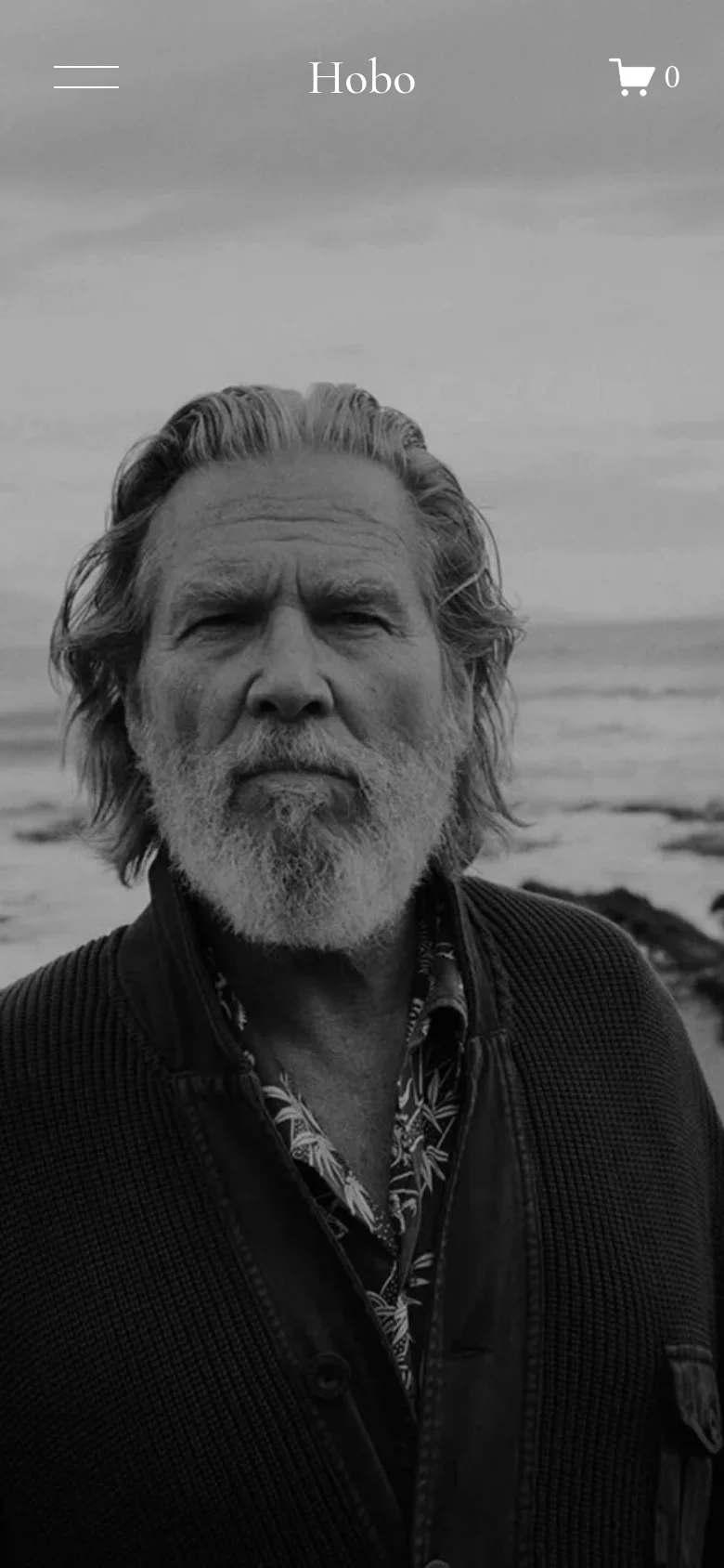 The mobile version displays the same black and white hero image of the man on the beach. The navigation is condensed into a hamburger menu icon on the left, with the 'Hobo' logo centered and a shopping cart icon on the right.