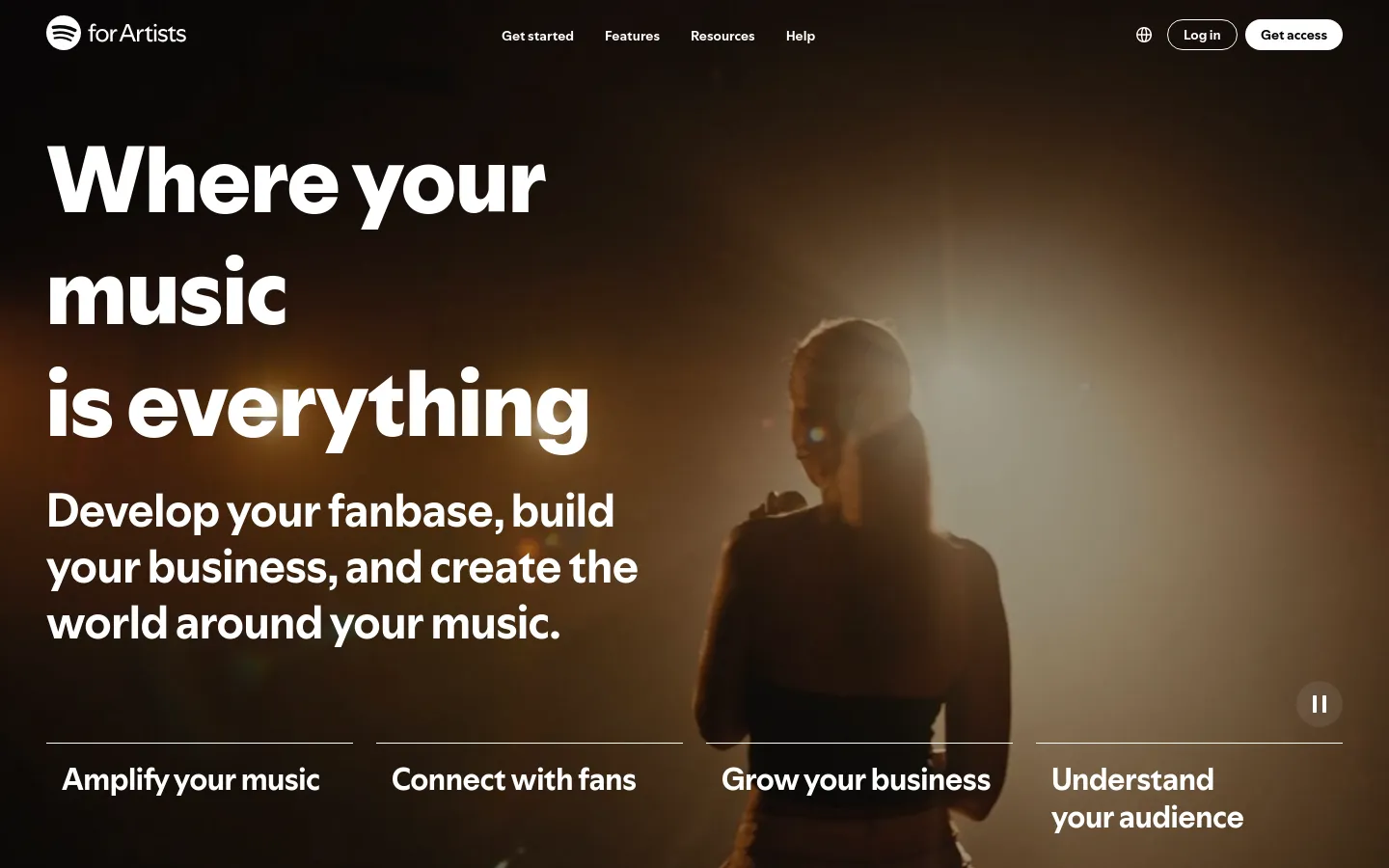 The desktop landing page features a dark, cinematic hero image of a musician under warm stage lighting with the headline 'Where your music is everything.' A navigation bar at the top includes links for Get started, Features, Resources, and Help, alongside 'Log in' and 'Get access' buttons. Four text-based navigation options—Amplify your music, Connect with fans, Grow your business, and Understand your audience—are arranged horizontally across the bottom of the hero section.
