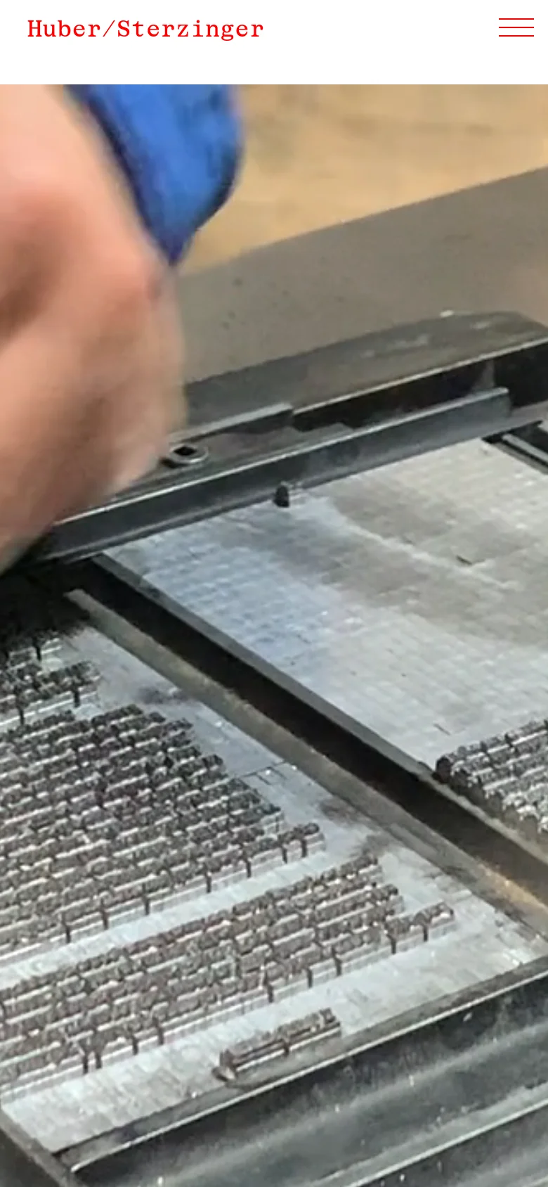 The mobile version displays a simplified layout with the 'Huber/Sterzinger' logo in red at the top left and a hamburger menu icon on the right. The hero image of hands using a printing press is cropped more tightly, focusing on the hands and the metal type, with the red title text appearing below the main image area.