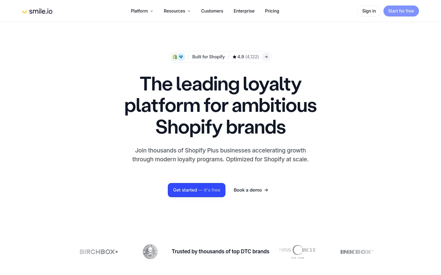 The desktop homepage features a clean, white background with a centered hero section. A large headline reads 'The leading loyalty platform for ambitious Shopify brands' above two primary calls to action: a blue 'Get started — it's free' button and a 'Book a demo' link. Below the hero, a row of grayscale brand logos is displayed under the text 'Trusted by thousands of top DTC brands'.