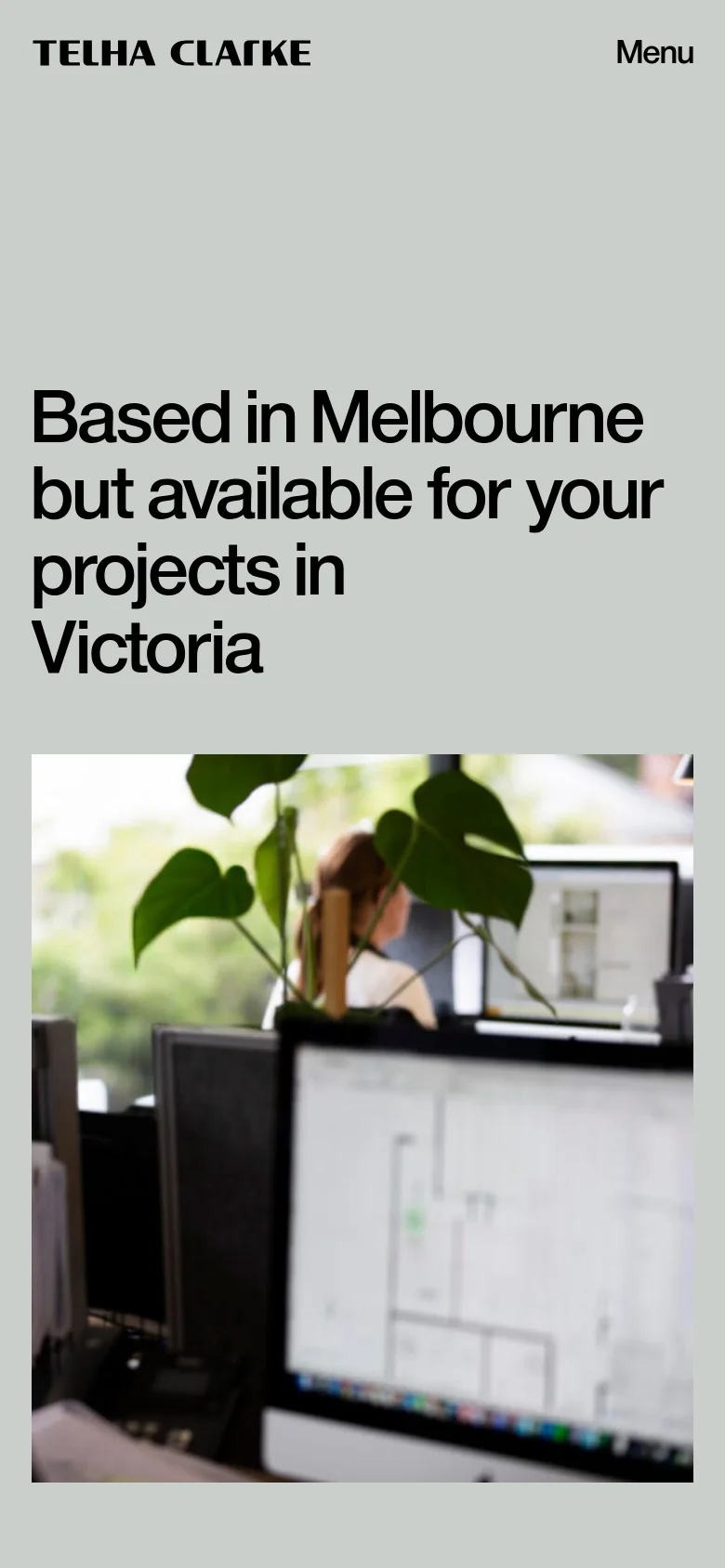 The mobile version simplifies the layout, placing the large bold headline at the top and a large, vertically oriented blurred office photograph below it. The navigation is condensed into a 'Menu' button at the top right, and the contact information is removed from the immediate view to prioritize the visual imagery.