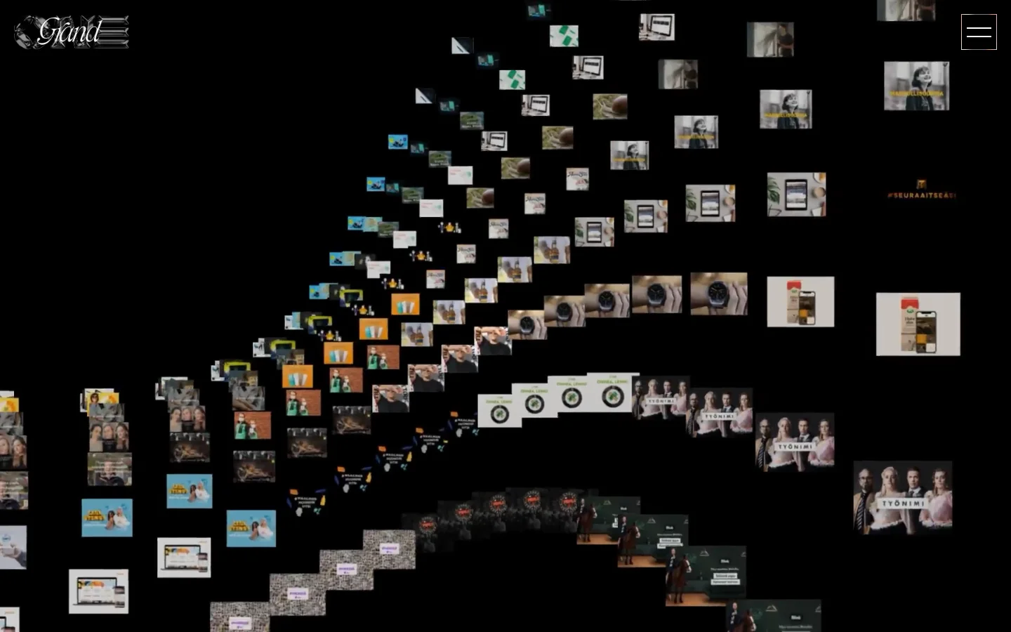The desktop homepage features a dark, minimalist aesthetic with a collage of various digital media works scattered across a black background. The Grand One logo is visible in the top left, and a hamburger menu icon is in the top right. The layout is non-linear, with images of different sizes and orientations creating a dynamic, artistic mosaic.