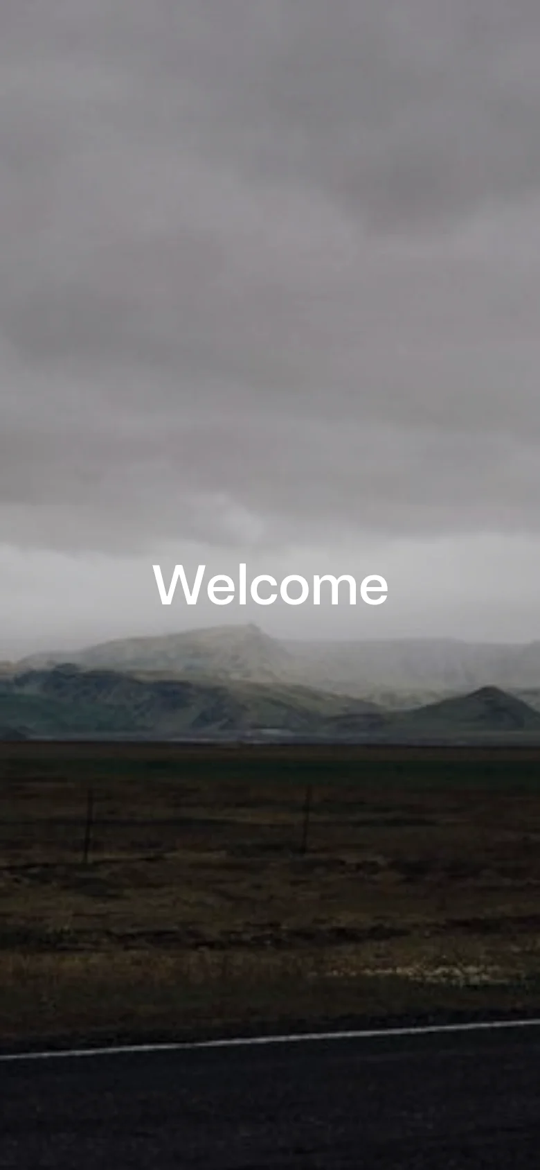 The mobile version maintains the same moody, overcast mountain landscape background and centered white 'Welcome' text. The layout is vertically compressed to fit the portrait aspect ratio, focusing the visual weight on the central text and the expansive sky.