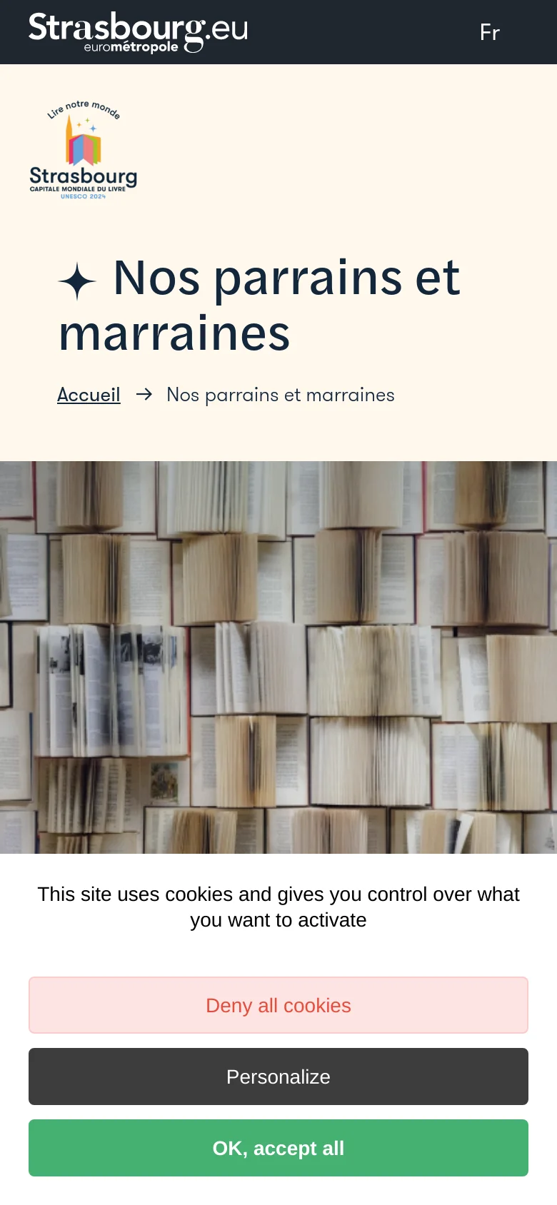 The mobile version presents a stacked layout with the Strasbourg logo and project branding at the top, followed by the large title 'Nos parrains et marraines' and breadcrumb navigation. Below the header, a large hero image shows a close-up texture of many open books standing side-by-side. A cookie consent banner with 'Deny all cookies', 'Personalize', and 'OK, accept all' buttons occupies the bottom of the screen.