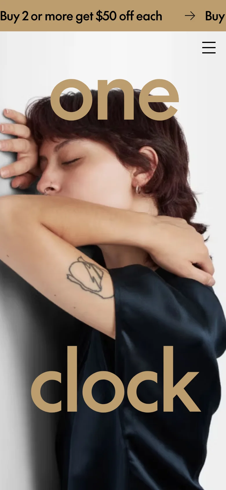 The mobile version presents a vertically stacked layout optimized for small screens, focusing on the large 'one clock' branding and the hero image of a person sleeping. The top promotional banner remains prominent, while the navigation menu is condensed into a hamburger icon in the top right corner. The cream and dark color palette is maintained for a clean, organic aesthetic.