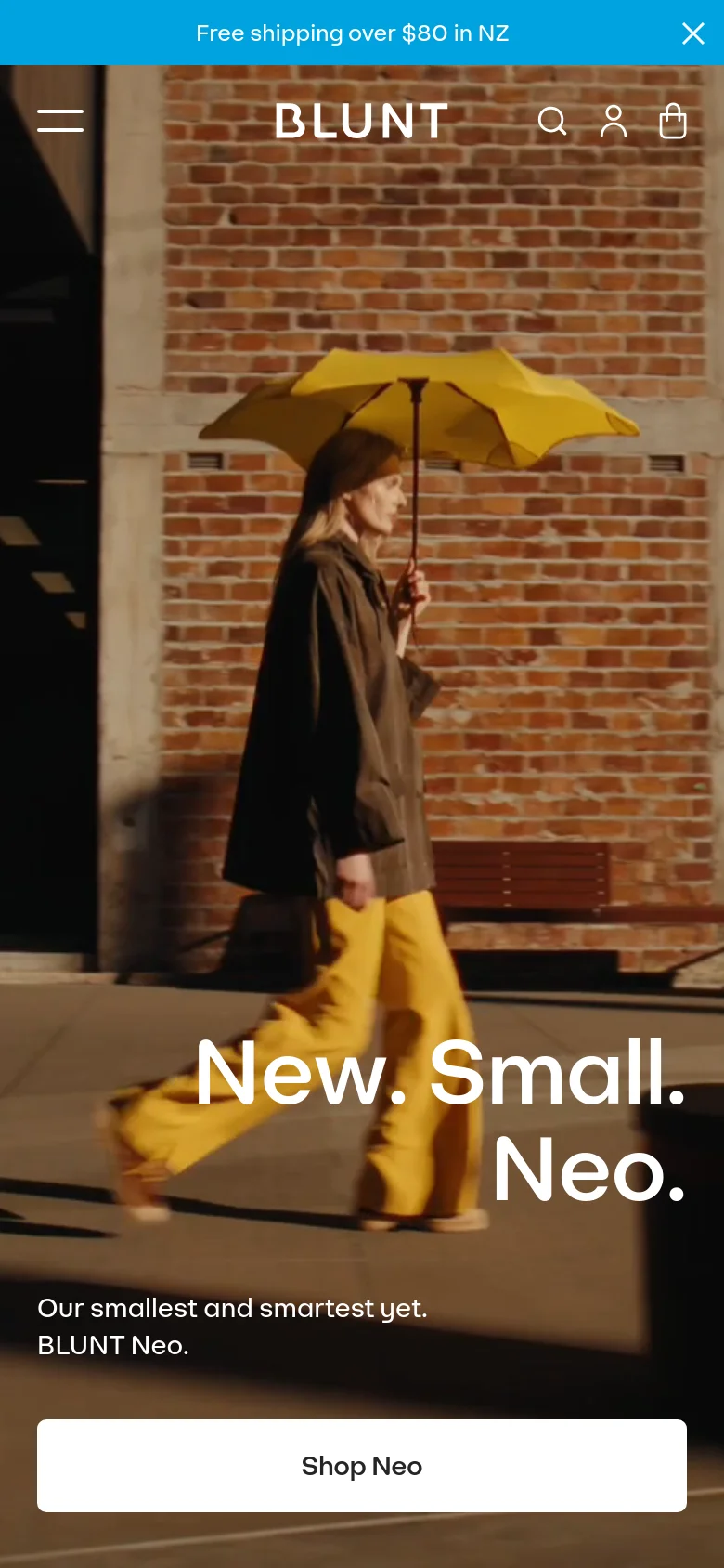 The mobile version displays a vertically oriented hero image of the person with the yellow umbrella, filling most of the screen. The headline 'New. Small. Neo.' and 'Shop Neo' button are centered over the image, and the navigation is condensed into a hamburger menu icon next to the BLUNT logo and search/account icons.