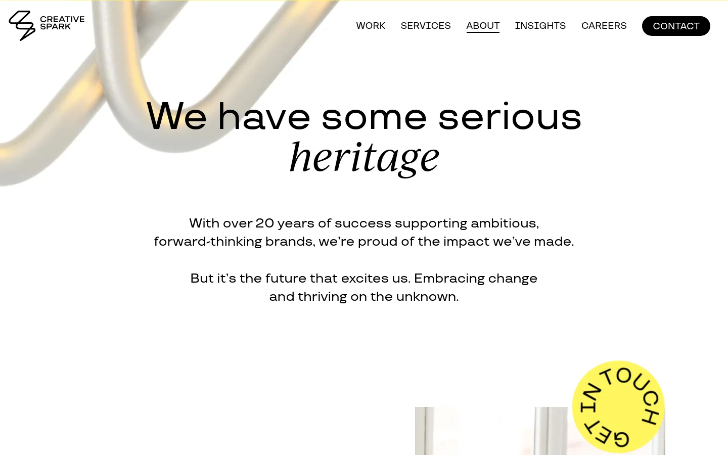 The desktop About Us page features a clean, minimalist layout with a white background and large, elegant serif typography. A hero section displays the headline 'We have some serious heritage' over an abstract, flowing metallic 3D shape, followed by a 'Get in Touch' call-to-action button. The navigation menu is positioned at the top right, including links for Work, Services, About, Insights, Careers, and a prominent Contact button.