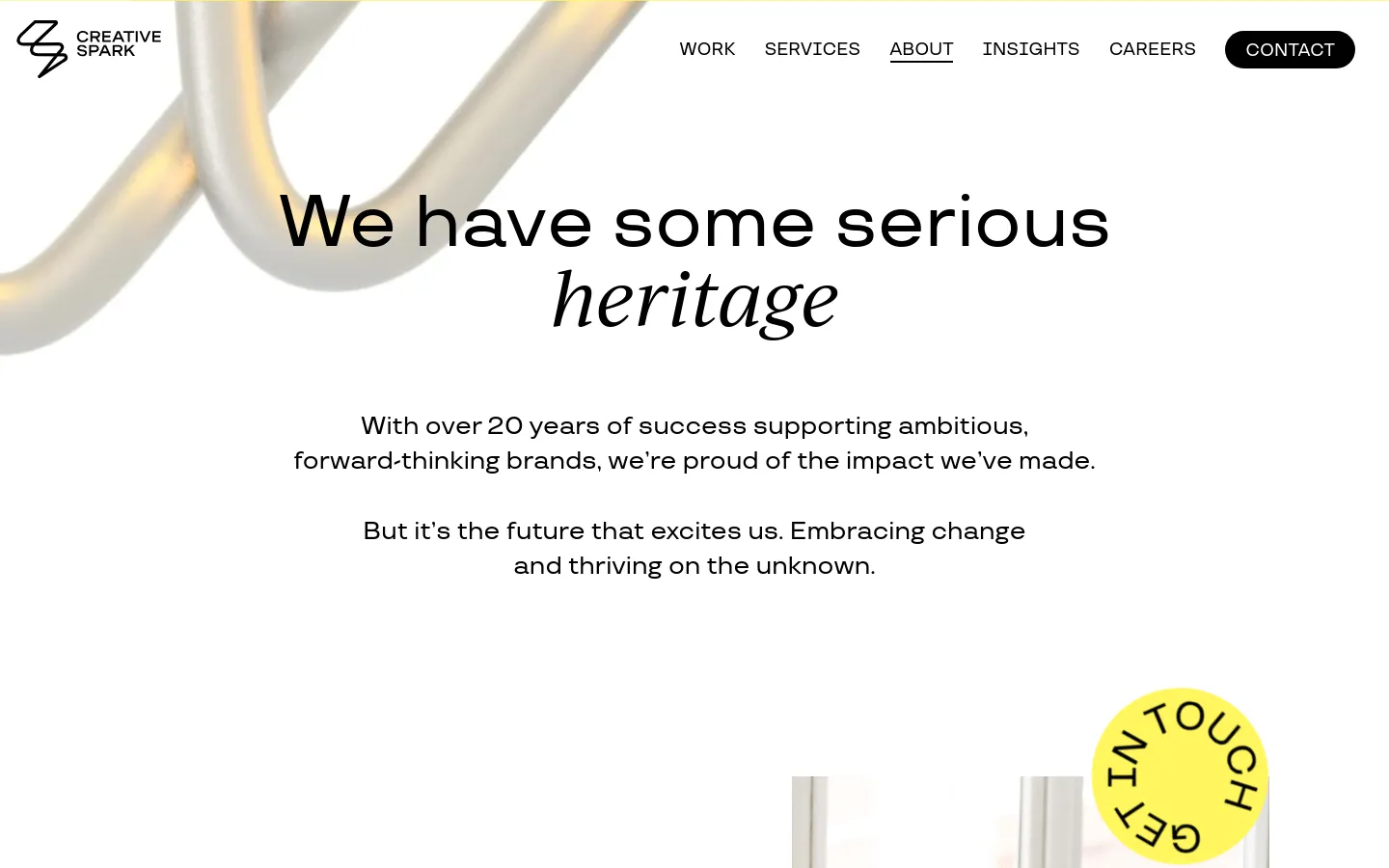 The desktop About Us page features a clean, minimalist layout with a white background and large, elegant serif typography. A hero section displays the headline 'We have some serious heritage' over an abstract, flowing metallic 3D shape, followed by a 'Get in Touch' call-to-action button. The navigation menu is positioned at the top right, including links for Work, Services, About, Insights, Careers, and a prominent Contact button.