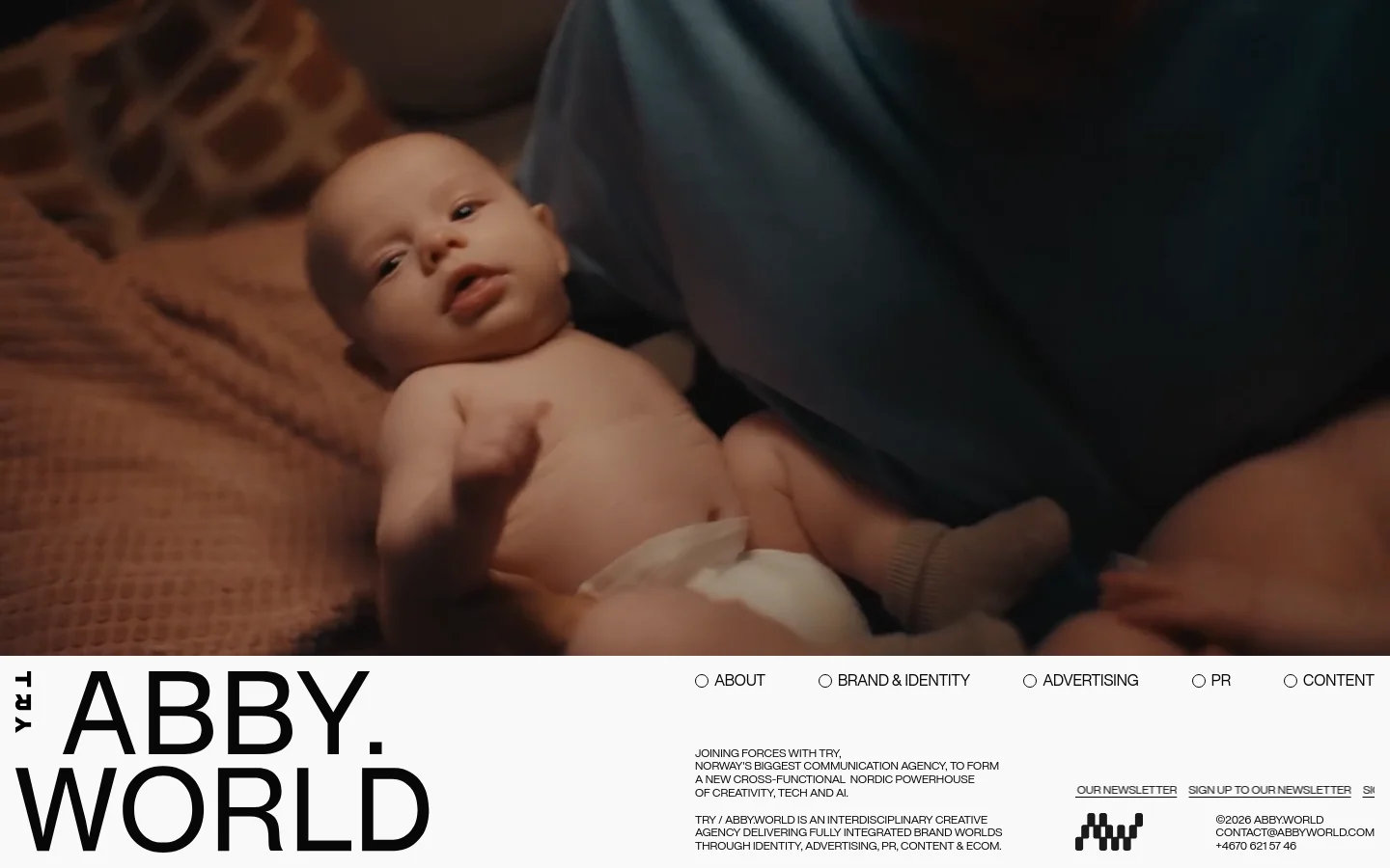 The desktop homepage features a large, cinematic hero video of a baby being held, set against a minimalist white background. The ABBY.WORLD logo is prominent in large black typography on the left, with a navigation menu including About, Brand & Identity, Advertising, PR, and Content on the right. A secondary section contains agency information and a call to action to sign up for the newsletter.