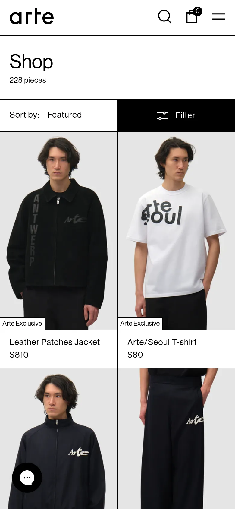 The mobile version presents a streamlined view with a condensed header containing the logo, search, shopping bag, and a hamburger menu. The product grid shifts to a two-column layout, displaying large vertical images of models wearing items like the Leather Patches Jacket and Arte/Seoul T-shirt. The 'Sort by' and 'Filter' options are prominent, spanning the width of the screen above the product list.