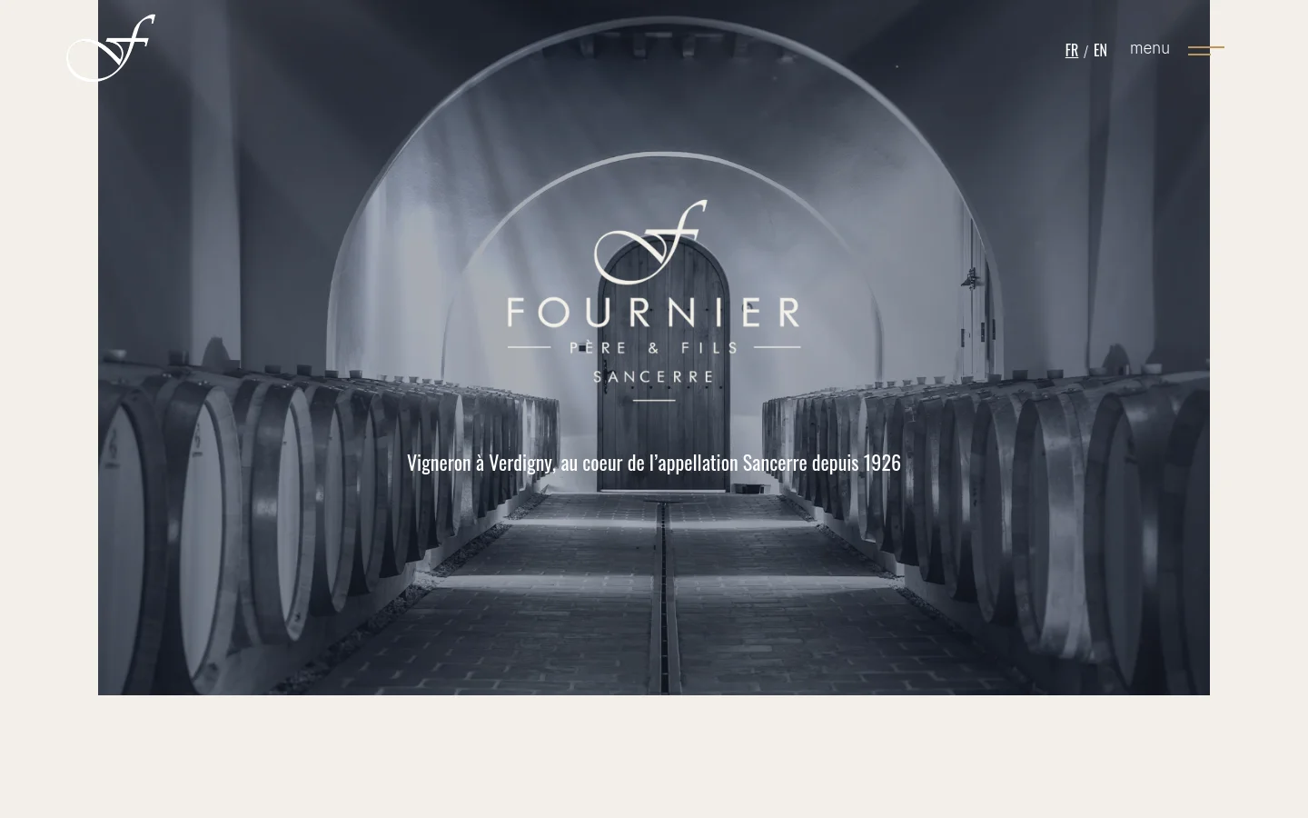 The desktop homepage features a large, grayscale hero image of a wine cellar with arched ceilings and rows of wooden barrels. The Fournier Père & Fils logo is centered over the image, accompanied by the headline 'Vigneron à Verdigny, au coeur de l'appellation Sancerre depuis 1926'. Navigation links for language selection and a menu icon are positioned at the top right.