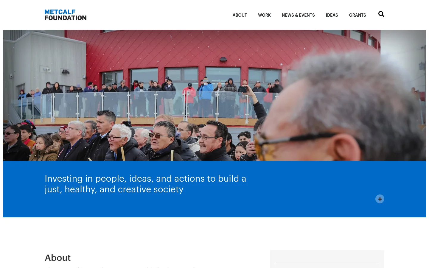 The desktop homepage features a large hero image of a diverse crowd of people in front of a red building, overlaid with a bright blue banner containing the headline 'Investing in people, ideas, and actions to build a just, healthy, and creative society'. A white navigation bar at the top includes the Metcalf Foundation logo and links for About, Work, News & Events, Ideas, and Grants, alongside a search icon.
