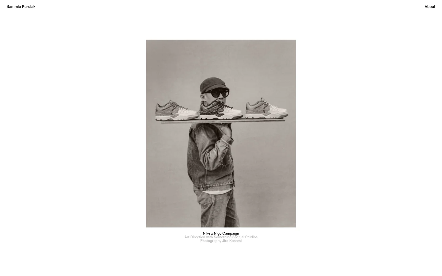 The desktop homepage features a minimalist white layout with the name 'Sammie Purulak' on the left and an 'About' link on the right. A large, centered black and white photograph shows a person wearing sunglasses and a cap, with Nike sneakers arranged on a reflective surface in front of them. Below the image, text credits the Nike x Nigo Campaign and art direction.