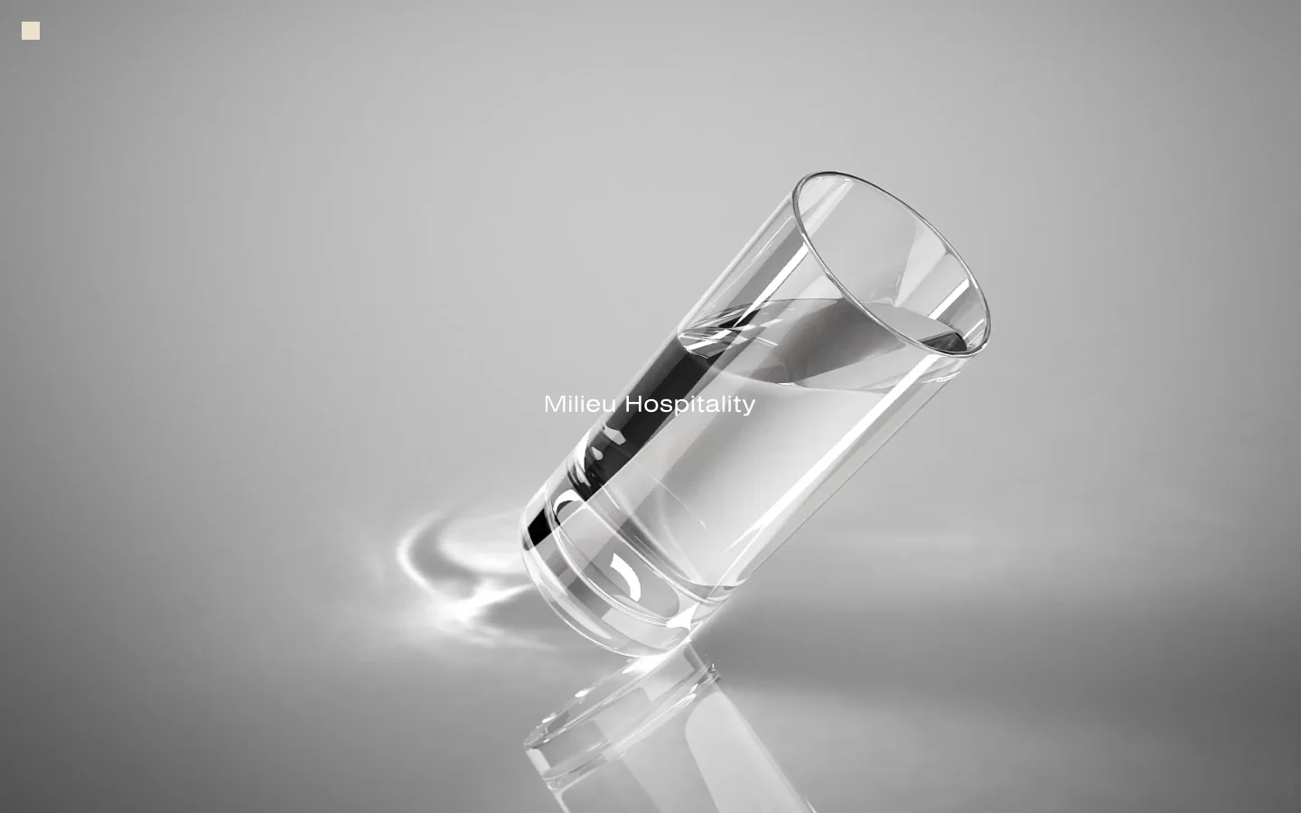 The desktop homepage features a minimalist design with a large hero image of a glass of water tilted on its side against a grey gradient background. The text 'Milieu Hospitality' is centered over the image, and a small menu icon is in the top left corner.