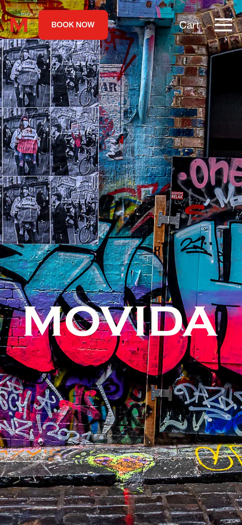 The mobile version displays a close-up, vertical view of the graffiti-covered walls and cobblestone ground, with 'MOVIDA' in large white text. The layout is simplified with a red 'BOOK NOW' button and 'Cart' text at the top, alongside a hamburger menu icon for navigation.