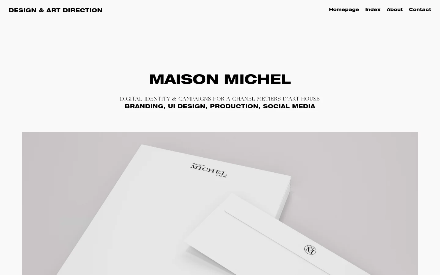 Desktop view of a minimalist portfolio page for Maison Michel featuring a white background and black typography. The layout includes a top navigation menu, a large centered headline, and a hero image showcasing white branded stationery and business cards. Below the imagery, descriptive text explains the digital identity and campaign work performed for the brand.