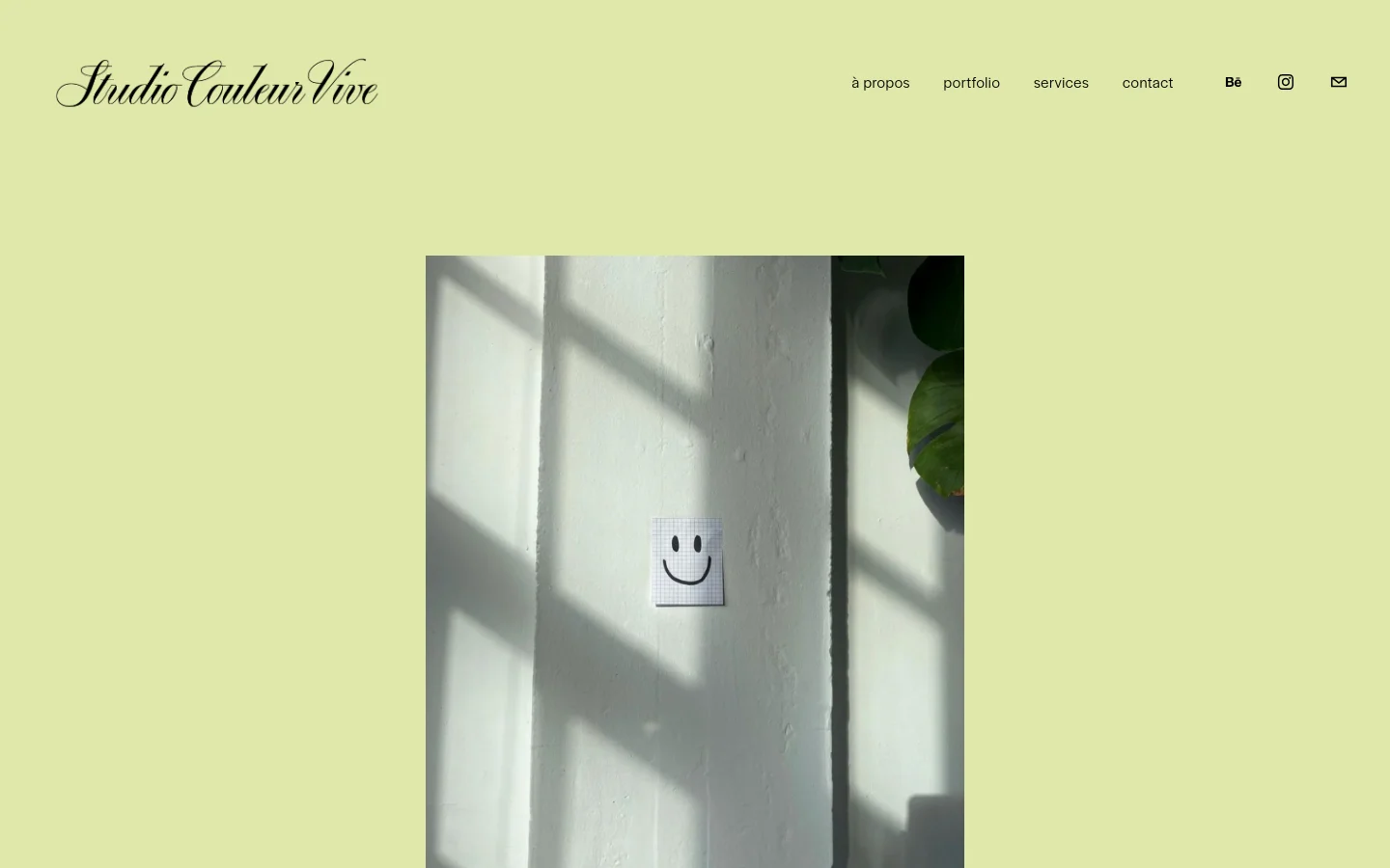 The desktop homepage features a light lime green background with the 'Studio Couleur Vive' logo in a black script font at the top left. A navigation menu with links like 'à propos' and 'portfolio' is at the top right, alongside social media icons. The central hero image shows a white wall with shadows, featuring a small piece of graph paper with a hand-drawn smiley face.