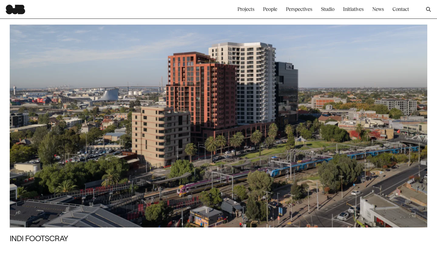 The SJB homepage features a minimalist white background with a navigation menu at the top right. A large hero image shows an aerial view of the Indi Footscray urban development, followed by a grid of large, high-quality images showcasing various architecture and interior design projects and news updates.