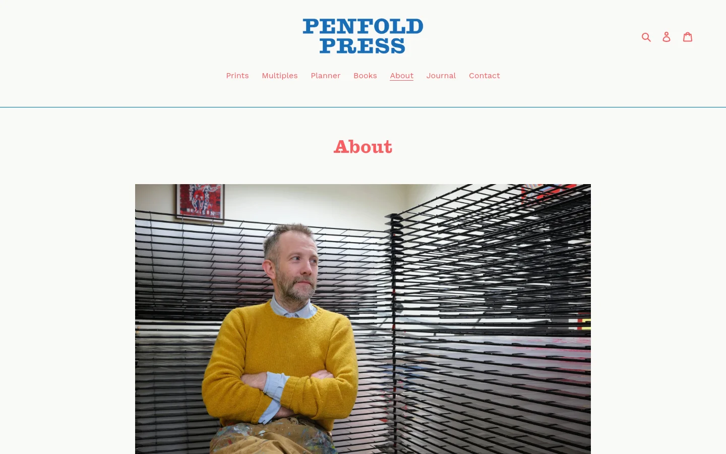 The About page features a centered red 'About' headline above a large portrait of Dan Bugg wearing a yellow sweater in a print studio. The layout is clean with a white background, a top navigation menu including links like Prints and Books, and a Penfold Press logo in blue. The text below the image describes the history and collaborative philosophy of the studio.
