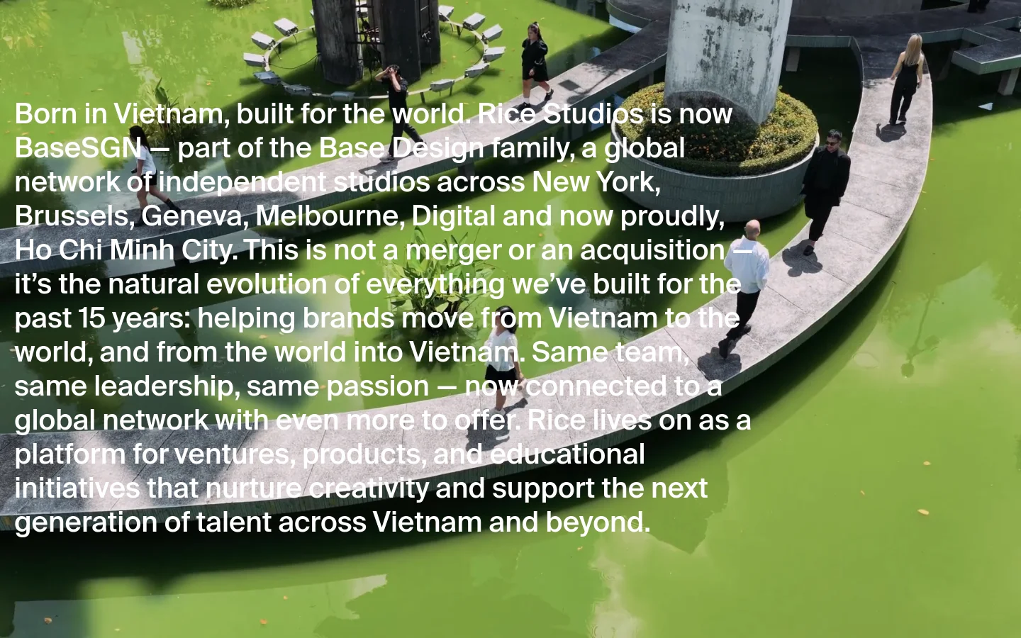 The desktop homepage features a large hero video background showing people walking on a curved concrete path over green water. A large white text block overlays the video, explaining Rice Studios' evolution into BaseSGN. The layout is minimalist with a clean, modern aesthetic.