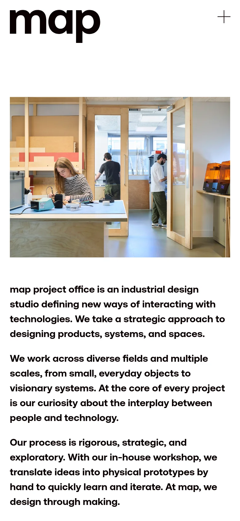 The mobile version presents a single-column layout with the 'map' logo and a plus icon at the top. The large hero image of the design studio spans the width of the screen, followed by the studio's descriptive text stacked vertically for easy reading on a small screen.