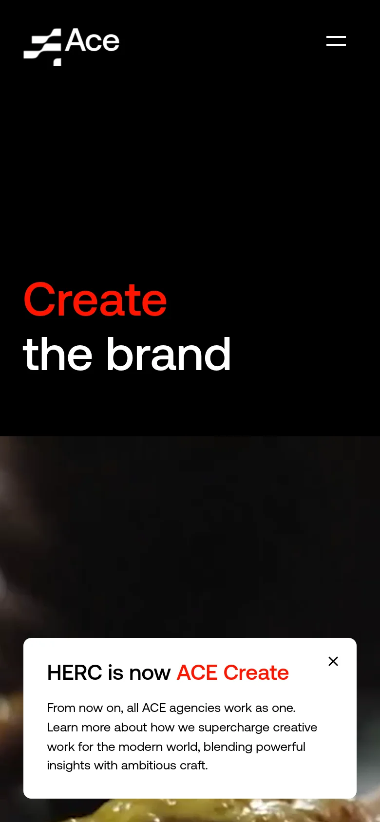 The mobile version maintains the dark theme and large 'Create the brand' headline but uses a simplified layout. The navigation menu is replaced by a white hamburger icon in the top right, and the announcement pop-up is centered at the bottom of the screen.