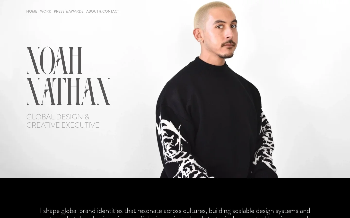 Desktop homepage for Noah Nathan, a Global Design & Creative Executive, featuring a large hero portrait of a man in a black graphic sweatshirt against a white background. The layout includes a minimalist navigation menu at the top left, large serif typography for the name, and a black section below containing a professional bio in white text.