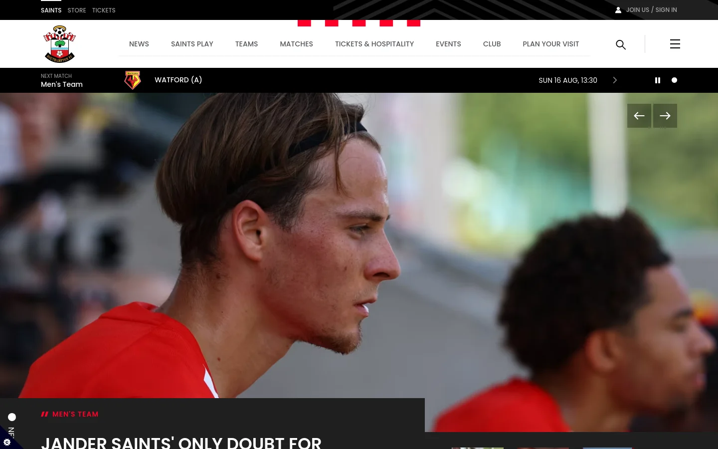 The Southampton FC homepage features a large hero image of a player in a red training kit, with a headline about Caspar Jander. A navigation bar at the top includes links for News, Teams, and Matches, alongside a 'Next Match' ticker showing Watford (A) on Sunday, August 16. The color scheme is primarily white, red, and black.