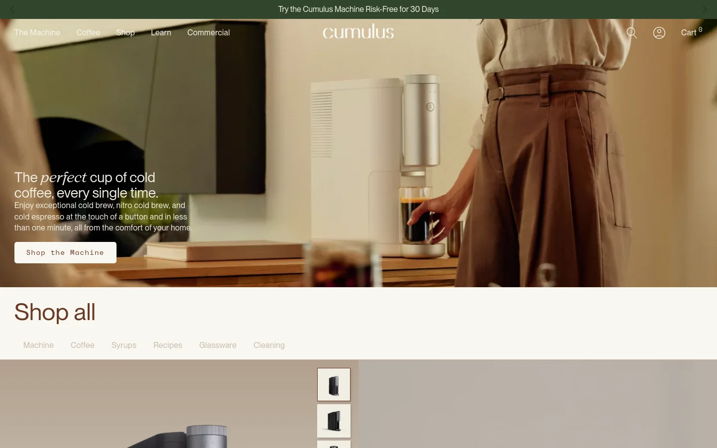 The desktop page features a hero image of a person using a sleek silver Cumulus coffee machine, overlaid with the headline 'The perfect cup of cold coffee, every single time' and a 'Shop the Machine' button. Below, a 'Shop all' section contains a horizontal text navigation menu for categories like Machine, Coffee, and Syrups, followed by a grid of product images. The color palette is warm and neutral with earthy tones.