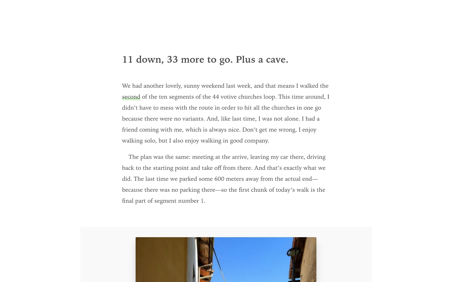 A blog post titled '11 down, 33 more to go. Plus a cave.' features a clean, minimalist layout with black text on a white background. The content includes several paragraphs of text interspersed with landscape photographs of streets and hillsides, with a large image partially visible at the bottom.