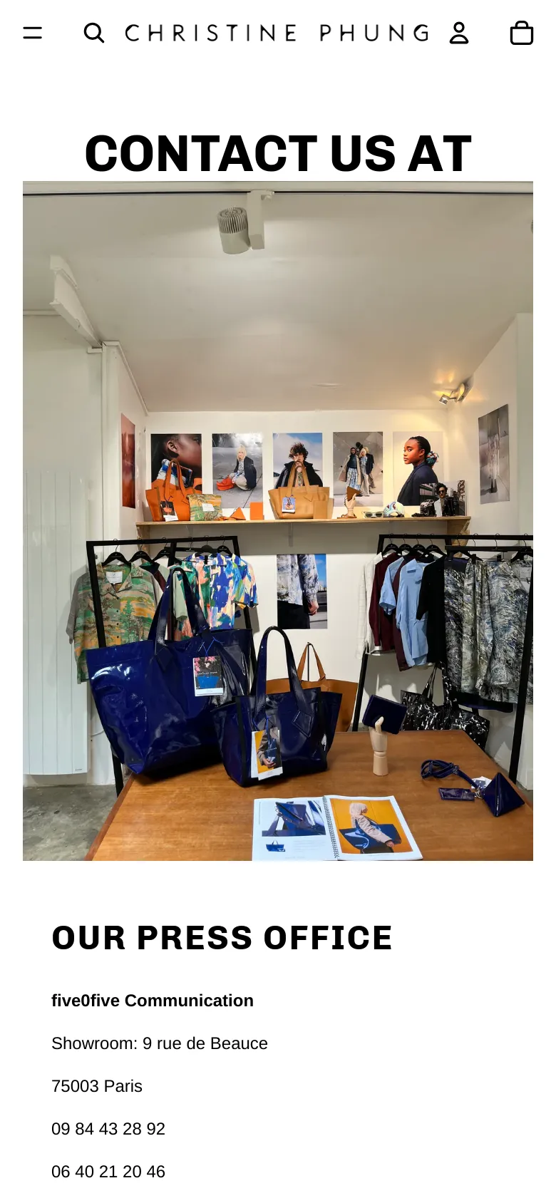 The mobile version stacks the content vertically, beginning with the 'CONTACT US AT' headline, followed by the large showroom photograph, and ending with the 'OUR PRESS OFFICE' contact information. The navigation menu is condensed into a hamburger icon and a search icon at the top.