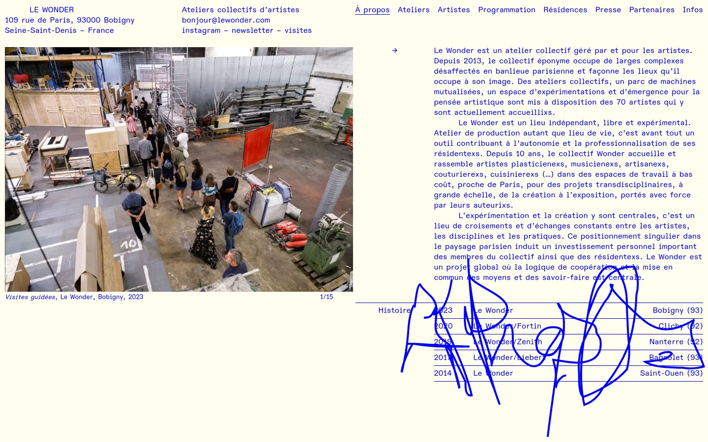 The desktop page features a minimalist design with blue text on a white background. A large hero image shows a wide shot of an industrial workshop filled with people and equipment, followed by a text section describing Le Wonder as a collective artist workshop. A sidebar on the right lists various locations and years, while the header contains navigation links and contact information.