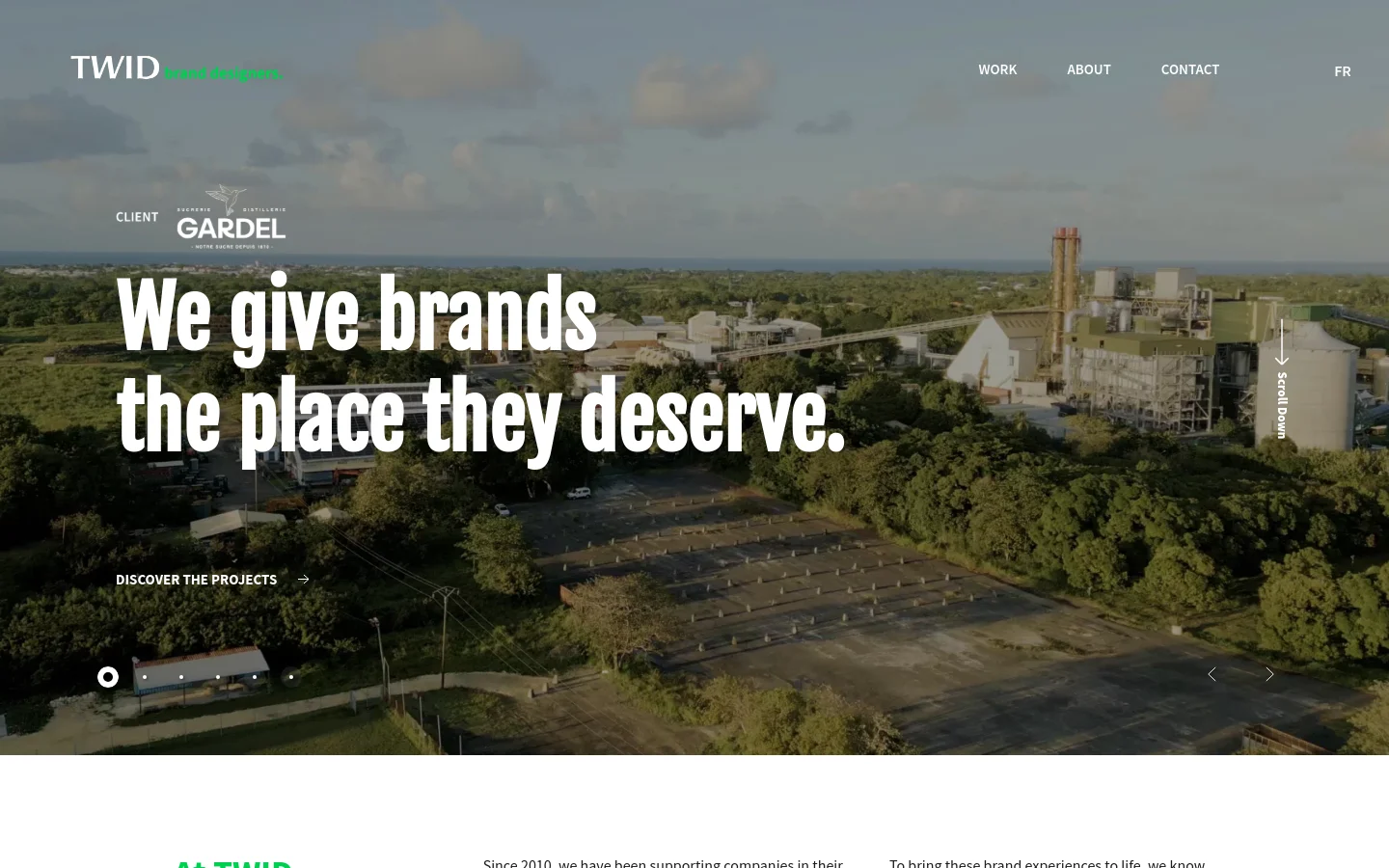 The desktop homepage features a full-width cinematic aerial photograph of an industrial landscape under a cloudy sky. A large white headline reads 'We give brands the place they deserve' over the image, with a 'DISCOVER THE PROJECTS' call to action below. The navigation menu is positioned at the top right with links for Work, About, Contact, and FR.
