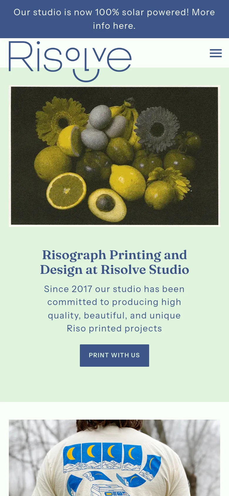 The mobile version uses a single-column vertical layout. The solar power announcement bar remains at the top, followed by the logo and a hamburger menu icon. The hero image of yellow fruit and flowers is centered above the main headline, description, and 'Print With Us' button, all set against a light mint green background.