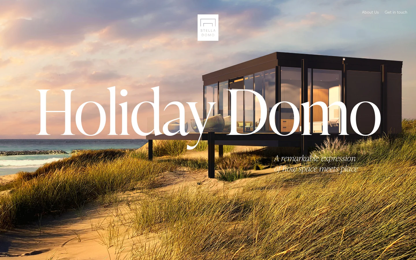 The Stella Domo homepage features a large hero image of a modern, glass-walled prefabricated bungalow situated on a sandy dune at sunset. The headline 'Holiday Domo' is displayed in large white serif text, accompanied by the subheadline 'A remarkable expression of how space meets place.' Navigation links for 'About Us' and 'Get in touch' are located in the top right corner against a soft sky background.