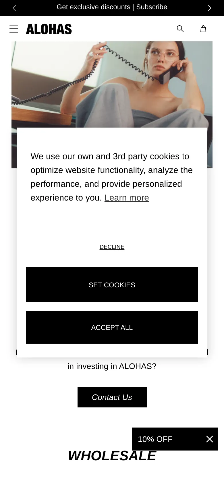 The mobile version presents a vertically oriented hero image of the woman on the phone, followed by a cookie consent overlay that covers much of the screen. The content sections for Investors, Wholesale, and Vendors are stacked vertically, maintaining the black button style and minimalist aesthetic of the desktop version.