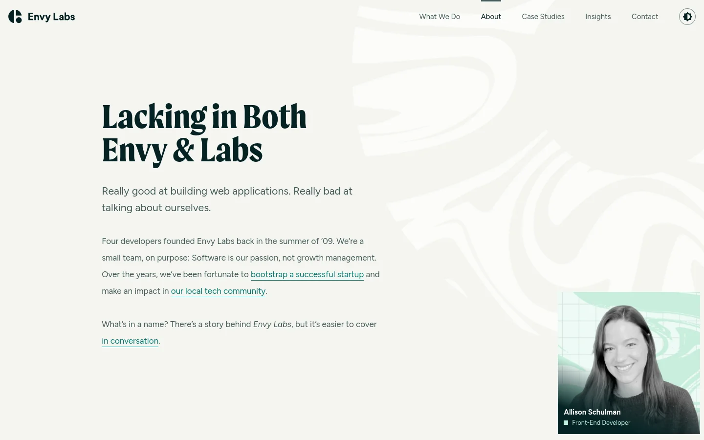 The About page features a minimalist design with a white and light grey color palette and a large, bold headline reading 'Lacking in Both Envy & Labs'. The layout includes introductory text with hyperlinks and a large portrait of Allison Schulman in the bottom right corner. A top navigation bar provides links to various site sections and a theme toggle.