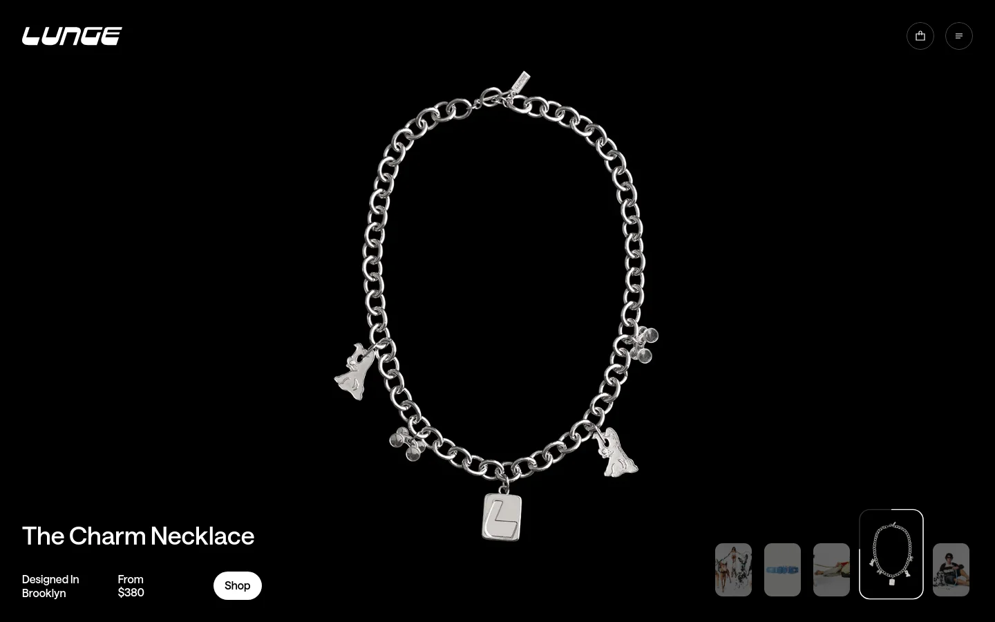 The LUNGE homepage features a minimalist black background with high-contrast white text and silver jewelry imagery. A large hero image showcases a silver charm necklace with various pendants, accompanied by the headline 'The Charm Necklace', pricing, and a white 'Shop' call-to-action button. The desktop layout includes a navigation bar at the top with the brand logo, a shopping bag icon, and a menu icon.
