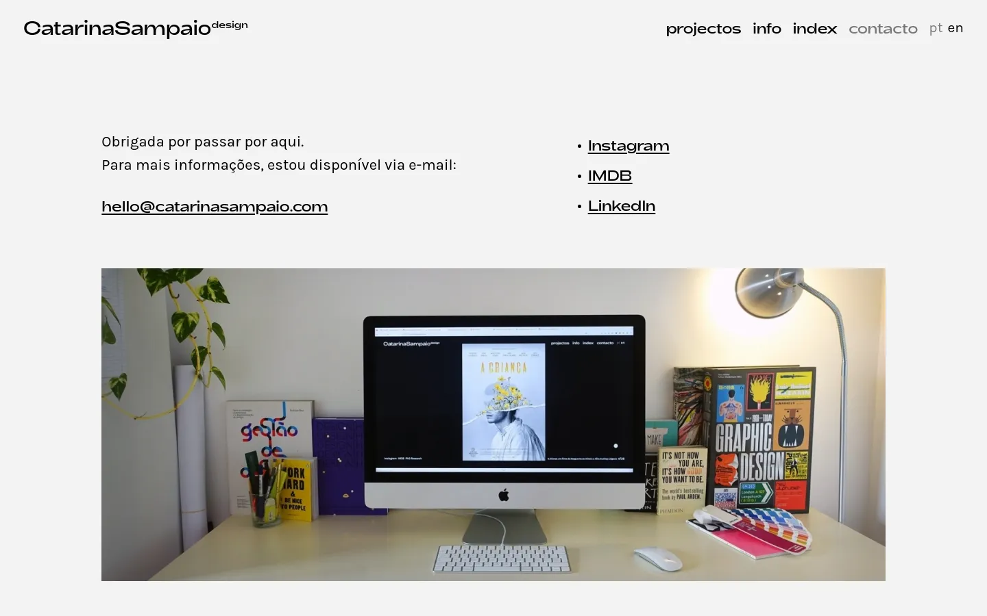 The desktop contact page features a minimalist white layout with the logo in the top left and navigation links on the right. Text on the left provides a greeting, an email link, and a list of social media links including Instagram, IMDB, and LinkedIn, positioned next to a large hero image of a designer's workspace with a computer and books.