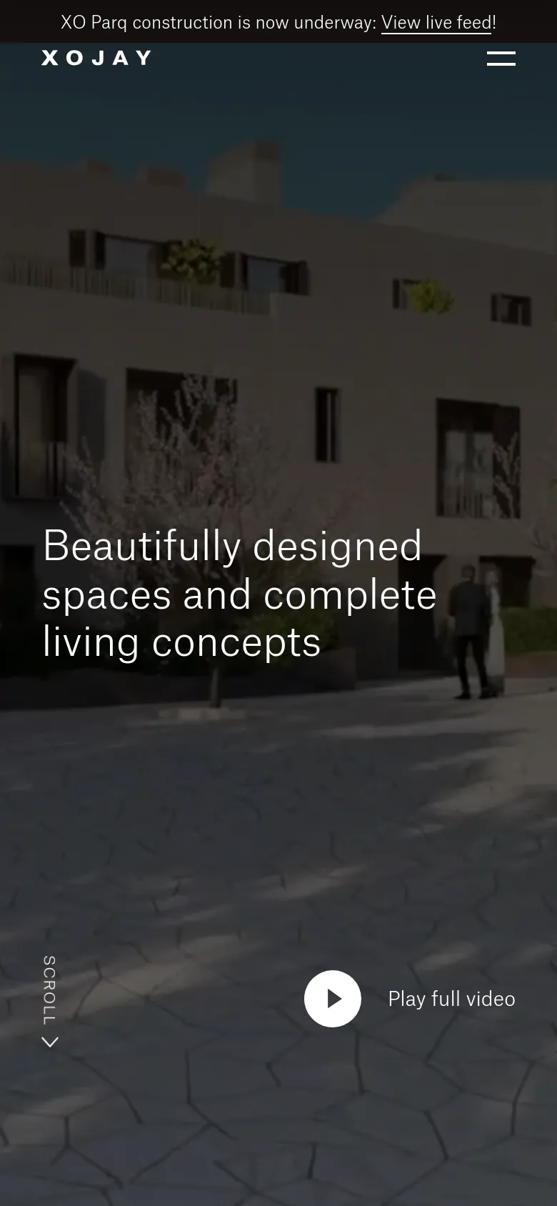 The mobile version presents a vertically oriented view of the same cinematic background, focusing on the building facade and courtyard. The headline is centered, and the navigation is condensed into a hamburger menu in the top right. The 'Play full video' button and 'Scroll' indicator are repositioned to fit the narrow screen layout.