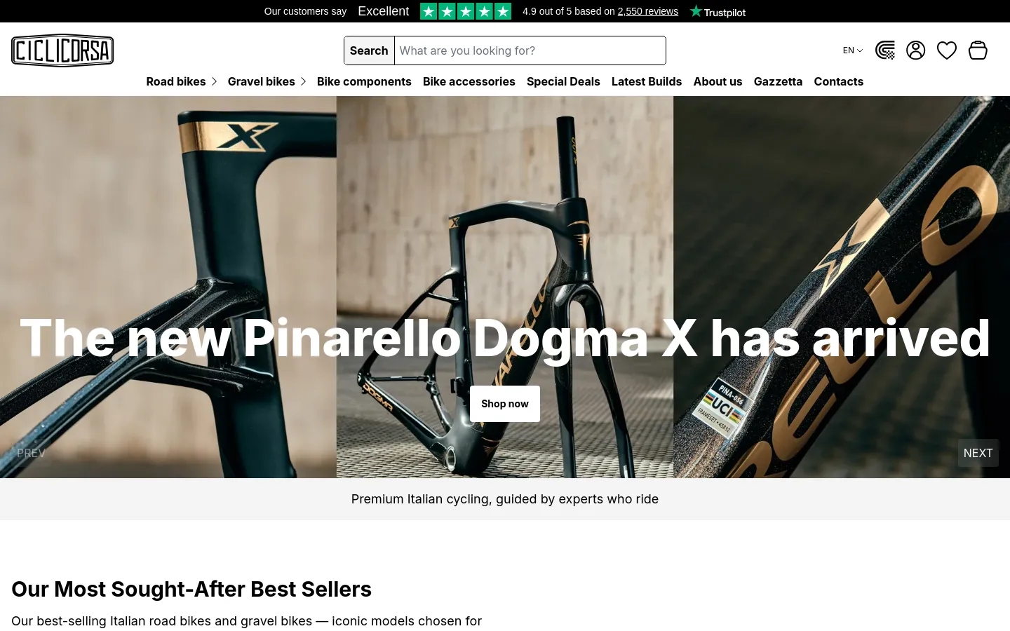 The desktop homepage features a large hero image of a black Pinarello Dogma X bike frame with gold accents. A prominent white headline reads 'The new Pinarello Dogma X has arrived' with a 'Shop now' button centered below it. The navigation bar includes a search field, brand logo, and links for Road bikes, Gravel bikes, and various components against a clean white background.